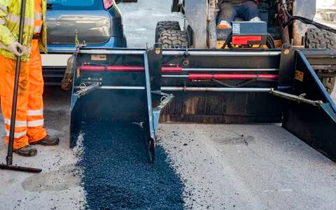 Worker regulate laying new asphalt to patch a bump in the road. Stock Photos