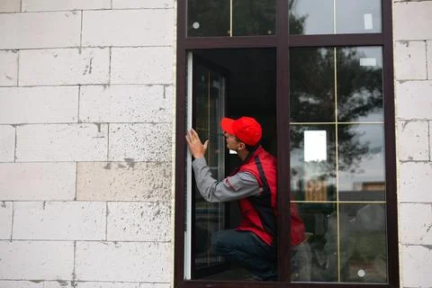 Worker regulates newly installed plastic window at home, ensures sealing an.. Stock Photos