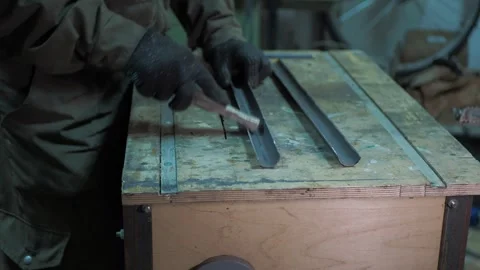 A worker removes burrs from a sawn pipe that is on a workbench. Stock Footage 312313932