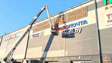 Worker removes old signs from large building in urban area during daylight hours Stock-Footage 327101945