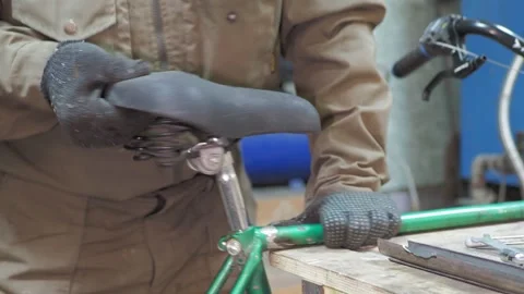 A worker removes the seat from an old bicycle along with the seatpost. Stock-Footage 317499092