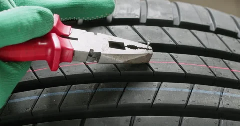 Worker removes sharp nail from tire using red pliers tool Stockbeeldmateriaal 314719211