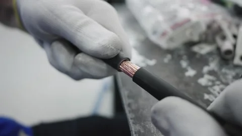 Worker removes stripped insulation from copper wire cable at production facil Stock Footage 319503863