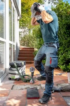 Worker removing ear protection while renovating outdoor patio tiles Stock Photos