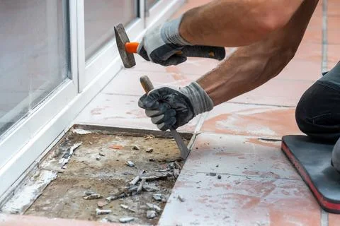Worker removing floor tiles with chisel during renovation Stock-Fotos