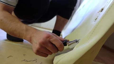 Worker removing old upholstery from part of the bed with staple remover Video stock 168643356