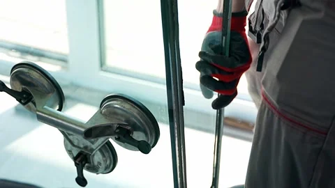 Worker removing one glass panel from triple glazed window unit during Stockbeeldmateriaal 344519645