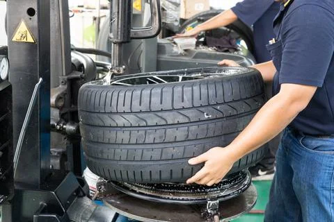 Worker removing tire from the rim using machinery at workshop Stock Photos