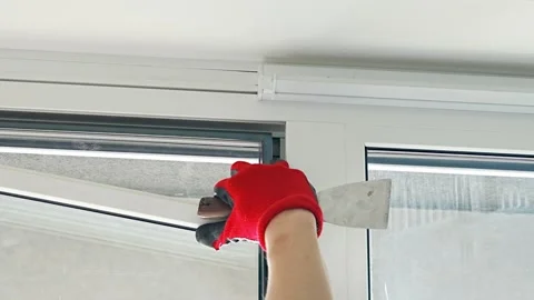 Worker removing window glazing bead from plastic frame during glass replacement Stockbeeldmateriaal 344519629