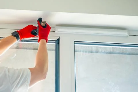 Worker removing window glazing bead from plastic frame during glass replacement Fotos Stock