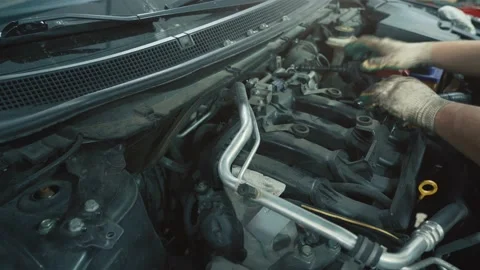 Worker repairing car and changes spark plugs in car engine in auto service Stock Footage 141551137