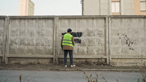 Worker repairing graffiti with tools and protective clothing. Urban technician Stock Footage 332507045