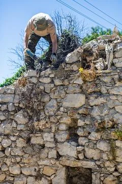 Worker Repairing Old Stone Wall With Power Tool On Sunny Day Wearing Gloves.. Stock-Fotos