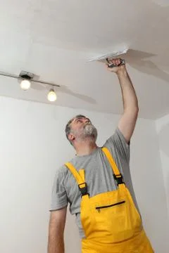 Worker repairing plaster at ceiling 库存照片