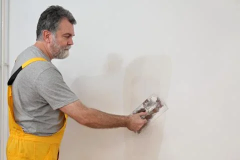 Worker repairing plaster at wall Stock Photos
