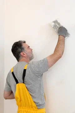 Worker repairing plaster at wall Stock Photos
