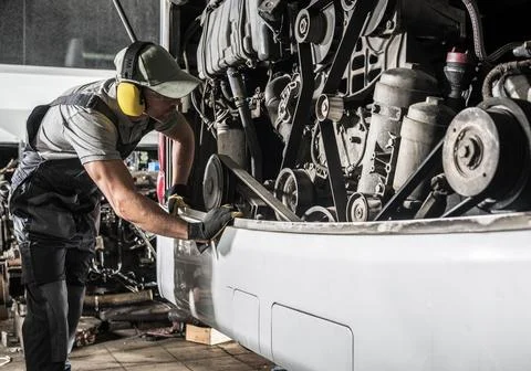 Worker Repairs Coach Bus Engine in Garage During Daytime Hours 스톡 사진