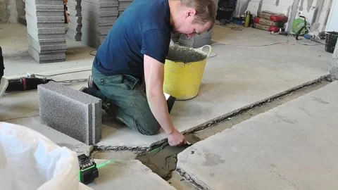 Worker repairs concrete floor with tools and materials in construction site duri Stock-Footage 332133262