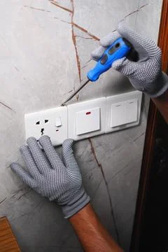 Worker repairs electrical switch in domestic setting Stock Photos