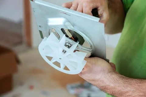 Worker repairs equipment in workshop while holding motor component in hand Stock Photos