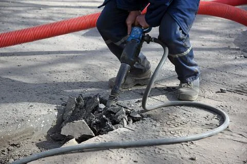 A worker repairs the road with a jackhammer. Stock Photos