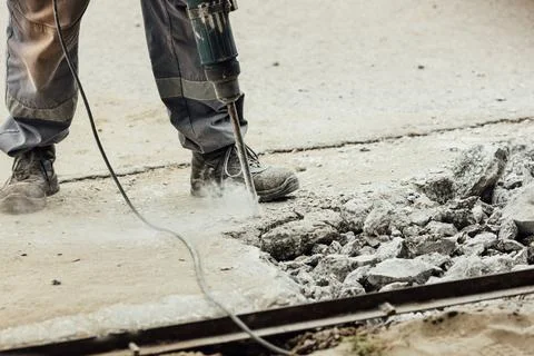 A worker repairs the road surface with a jackhammer on a summer day Stock-Fotos