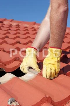 Worker replacing roof tiles on house Stock Photos
