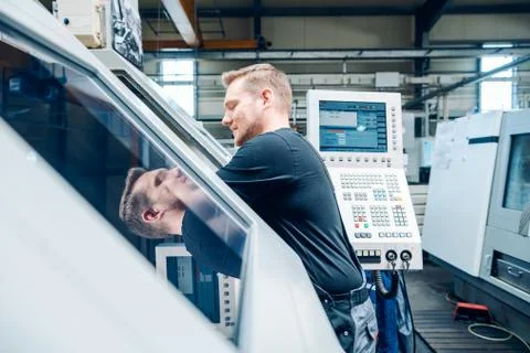 Worker resetting a cnc lathe machine in manufacturing factory Stock Photos