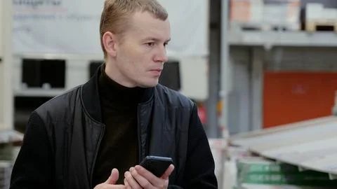Worker at retail warehouse using smartphone app to check inventory while Stock Photos