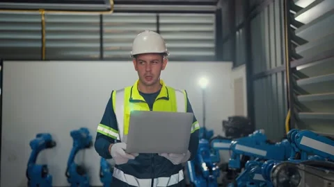Worker reviews data on laptop near industrial robots 스톡 동영상 344920065