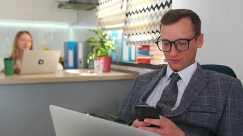 Worker reviews smartphone and computer, manager examines smartphone while laptop Stock Footage 319980017