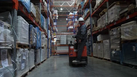 The worker rides along the row along the high racks with the products. 4K Slow 库存影片 111766548