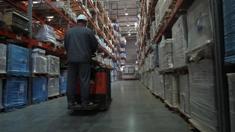 The worker rides on the square between the shelves filled with boxes of goods Video stock 111767827