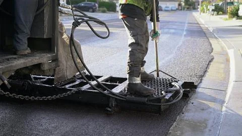 Worker riding on machine applying slurry seal Stock Photos