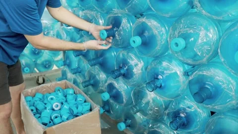 A worker rips off the caps from the open necks of PET bottles.  Stock Footage 158339187