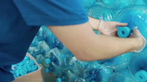 A worker rips off the caps from the open necks of PET bottles. Stock Footage 158339196