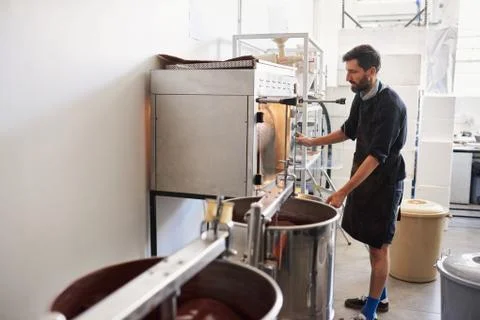 Worker roasting cocoa beans while working in a chocolate factory Stock Photos