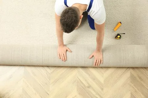 Worker rolling out new carpet flooring indoors, top view Stock Photos