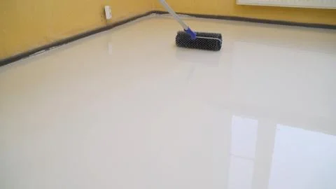 Worker rolls liquid floor. Needle roller for bulk floors. A worker fills the  Stock Photos