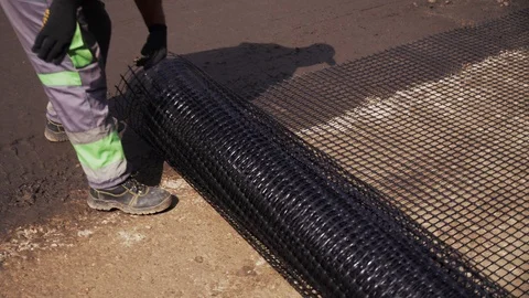 Worker rolls the mesh on the road before laying the asphalt Video stock 95225432