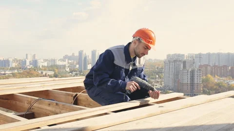 Worker on a roof with electric drill installing tile on wooden house Stock Footage 68421409