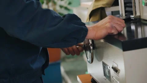 A worker rotates a handle while sitting at a machine in a factory Stock Footage 155211300
