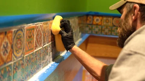 Worker rubs tiles intently to take off excess grout on the face of the Stock Footage 101434721