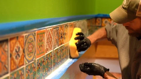 Worker rubs tiles with a wet sponge to take off excess grout. Stock Footage 101434760