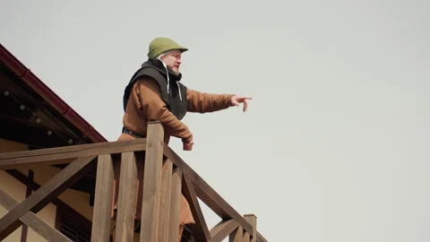 Worker on rustic wooden balcony leaning forward and pointing downward during Stock Footage 343681965