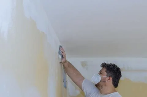 Worker sanding the drywall mud using sand trowel during renovation the house Stock Photos