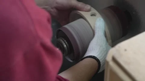 Worker sanding a wooden drum shell on a rotating polishing machine in a Stock Footage 341596729