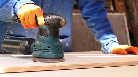 Worker sands wooden surface with random orbital sander Видео 335028169