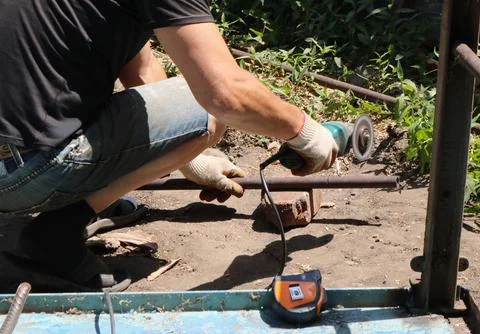 A worker sawed off part of a metal pipe with a grinder Stock Photos