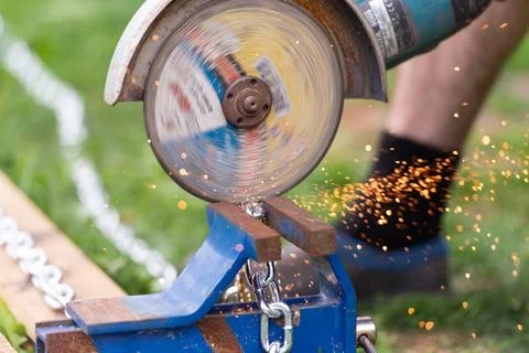 A worker saws a chain with a grinder Stock Photos